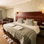 Angled view of Double bed, desk, HDTV, slippers and dressing gowns in a Privilege Room at Mercure Hotels