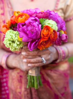 An indian bride holding a beautiful bouquet of colourful flowers