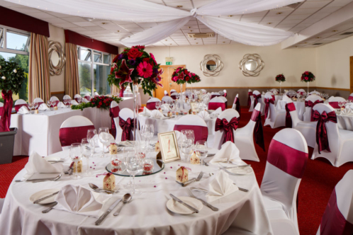 Tables set in red for a wedding breakfast at Mercure Maidstone Great Danes Hotel