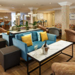 Bar and lounge area at Mercure Maidstone Great Danes hotel with bottle of fizz and two glasses on table.