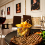 Blurred steak and chips in restaurant area at Mercure Maidstone Great Danes Hotel.