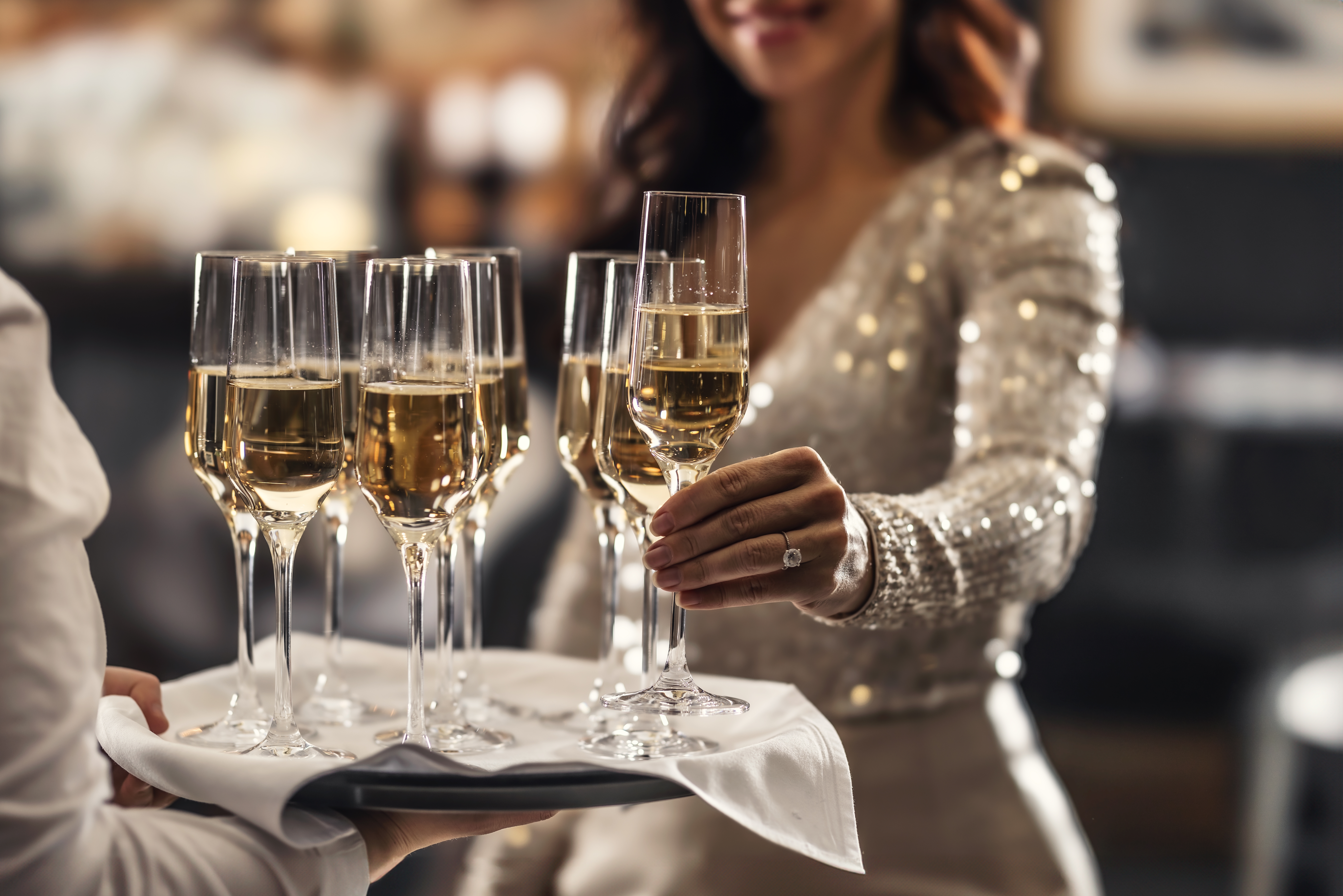 A,Bartender,Holds,A,Plate,With,Pink,Champagne,And,A People celebrating new years eve